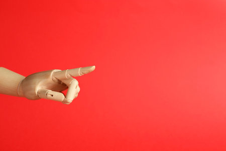 Wooden mannequin hand on red background. Space for textの写真素材