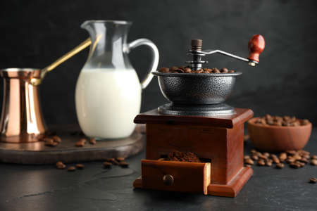 Vintage manual coffee grinder with beans and powder on black tableの写真素材