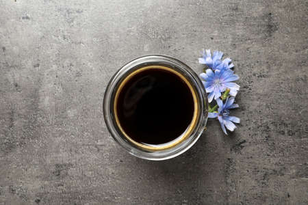 Delicious chicory drink and flowers on gray table, flat lay