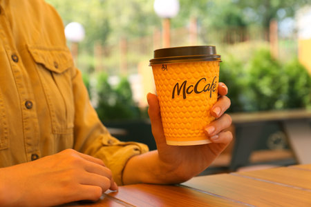 MYKOLAIV, UKRAINE - AUGUST 11, 2021: Woman with hot McDonald's drink in outdoor cafe, closeupのeditorial素材