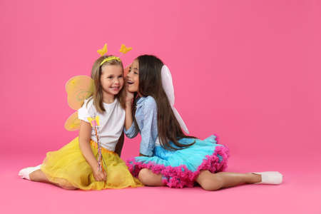 Cute little girls in fairy costumes with wings on pink backgroundの写真素材