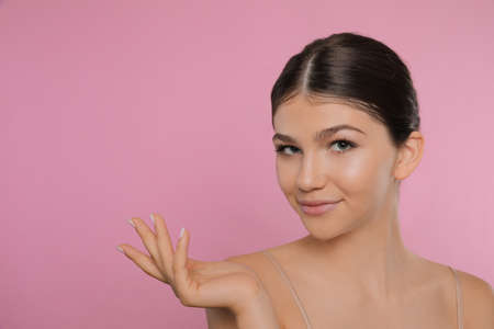 Portrait of pretty girl on pink background, space for text. Beautiful face with perfect smooth skin
