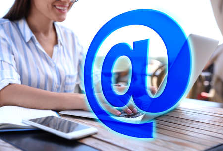 At sign illustration and woman sending email via laptop at table, closeup