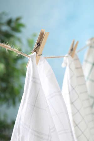 Washing line with wooden clothespins and fabrics against blurred backgroundの写真素材
