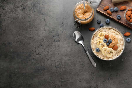 Tasty oatmeal porridge with toppings served on gray table, flat lay. Space for textの写真素材