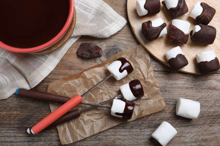 Delicious marshmallows covered with chocolate on wooden table, flat layの写真素材