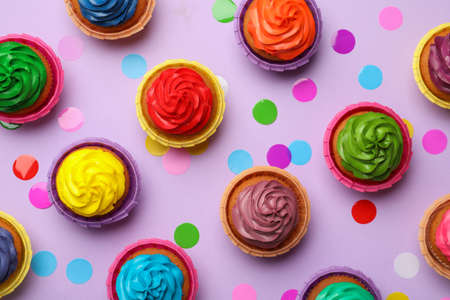 Many delicious colorful cupcakes and confetti on violet background, flat layの写真素材