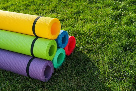 Bright exercise mats on fresh green grass outdoors, space for textの写真素材