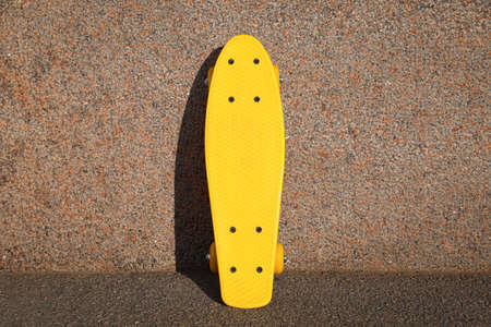 Stylish yellow skate board near wall outdoorsの写真素材