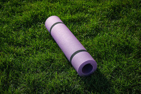 Bright exercise mat on fresh green grass outdoors