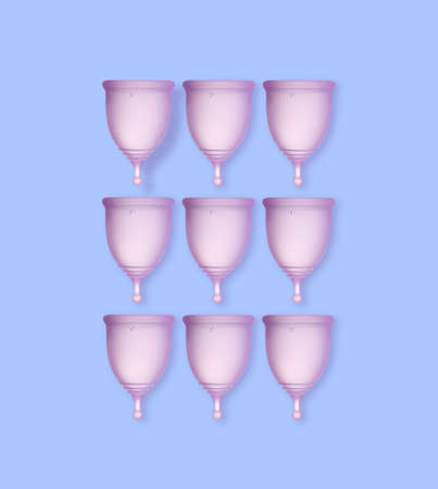 Many purple menstrual cups on light blue background, flat layの写真素材