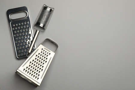 Different modern graters on gray background, flat lay. Space for textの写真素材
