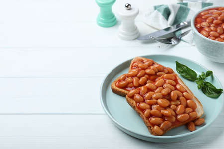Toasts with delicious canned beans on white wooden table, space for textの写真素材