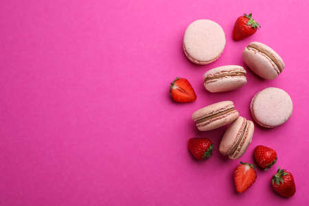 Delicious macarons and fresh strawberries on pink background, flat lay. Space for textの写真素材
