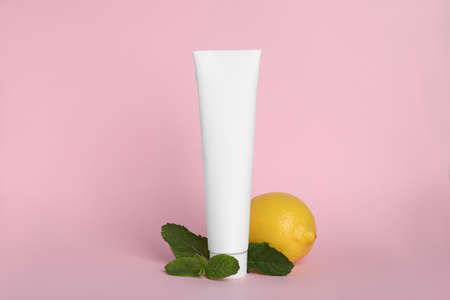 Blank tube of toothpaste, fresh mint and lemon on pink backgroundの写真素材