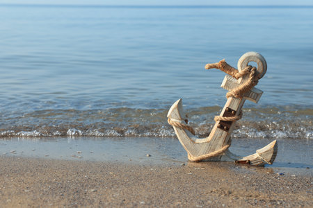 Wooden anchor with rope on sand near sea. Space for textの写真素材