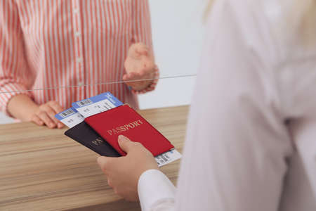 Agent giving passports with tickets to client at check-in desk in airport, closeupの写真素材