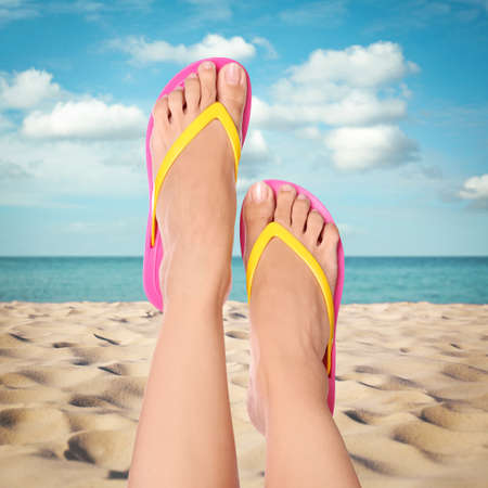 Woman wearing stylish flip flops resting on sandy beach and enjoying beautiful seascape, closeupの写真素材