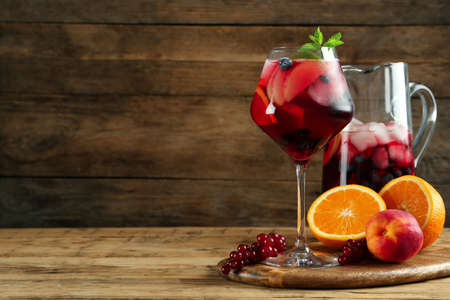 Glass and jug of Red Sangria with fruits on wooden table, space for textの写真素材