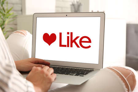 Woman using laptop with word Like on screen indoors, closeup