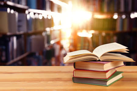 Many books on wooden table in library. Space for text