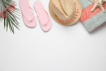 Beach towel, flip flops, hat and sunglasses on white background, flat lay. Space for text