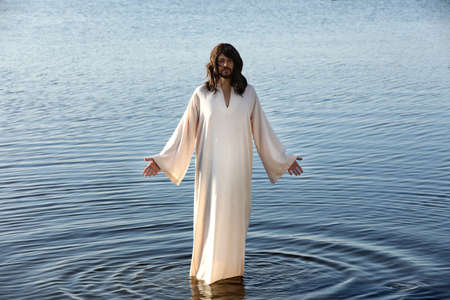 Jesus Christ in water lit by morning sunの写真素材