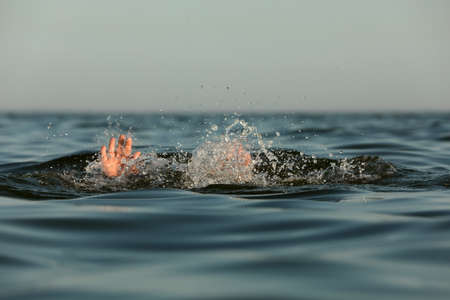 Drowning man reaching for help in seaの写真素材
