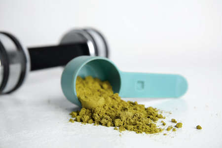 Measuring scoop with hemp protein powder on white tableの写真素材
