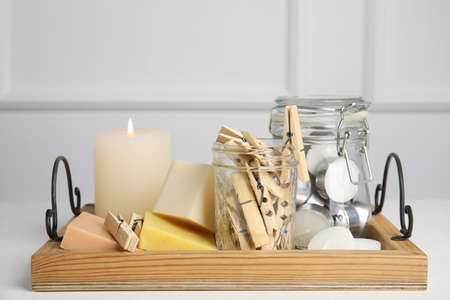 Wooden tray with many clothespins, candles and soap bars on white table