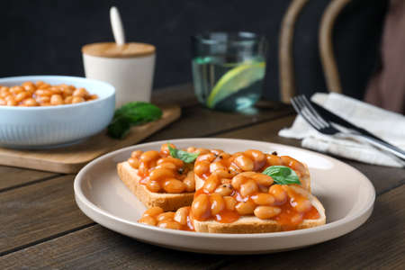 Toasts with delicious canned beans on wooden tableの写真素材