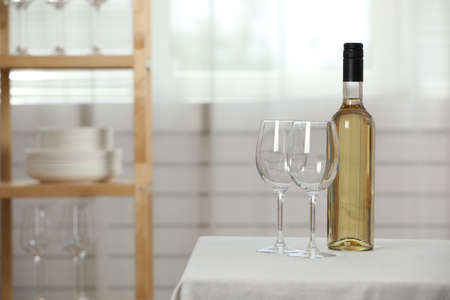 Bottle of wine with two glasses on table indoors