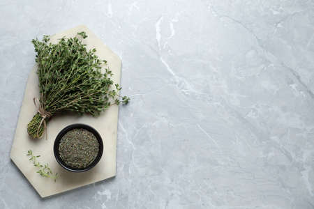 Bowl with dried thyme and fresh herb on light table, top view. Space for textの写真素材