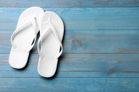 Stylish beach flip flops on blue wooden background, flat lay. Space for text