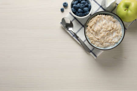 Tasty oatmeal porridge served on light wooden table, flat lay. Space for textの写真素材