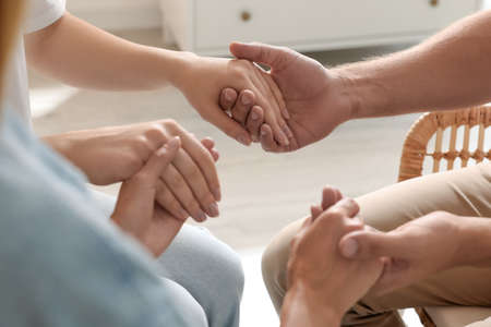 Group of religious people holding hands and praying together indoors, closeupの写真素材
