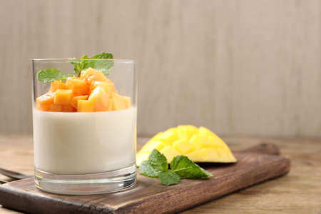 Delicious panna cotta with mango on wooden table. Space for textの写真素材