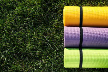Bright exercise mats on fresh green grass outdoors, flat lay. Space for textの写真素材