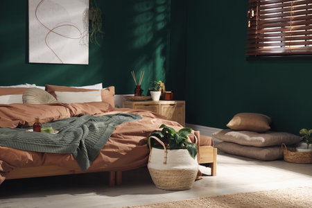 Stylish interior with large comfortable bed and potted plantsの写真素材