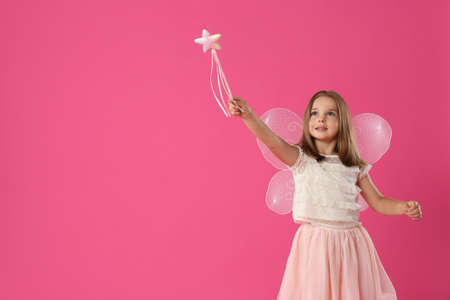 Cute little girl in fairy costume with wings and magic wand on pink background. Space for textの写真素材