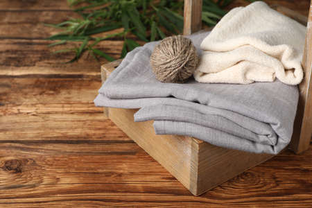 Hemp cloths and woolen yarn in crate on wooden table, space for textの写真素材