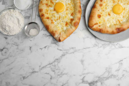 Fresh homemade khachapuri and ingredients on white marble table, flat lay. Space for textの写真素材
