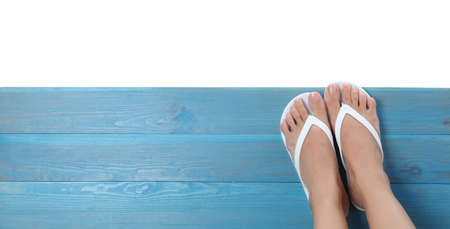 Woman wearing stylish flip flops on turquoise wooden deck against white background, top viewの写真素材