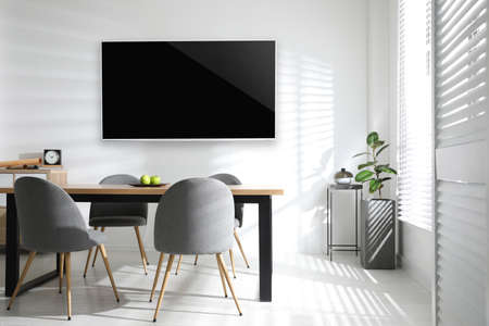 Modern wide screen TV on white wall in room with stylish furnitureの写真素材