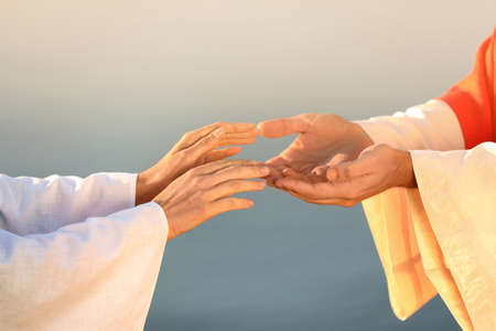 Woman reaching for Jesus Christ's hands near water outdoors, closeup
