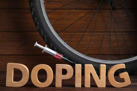 Word Doping, syringe and bicycle wheel on wooden backgroundの写真素材
