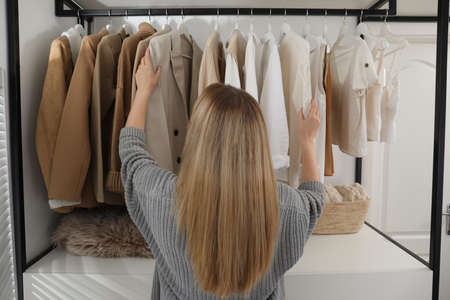 Young woman choosing outfit in dressing room, back viewの写真素材