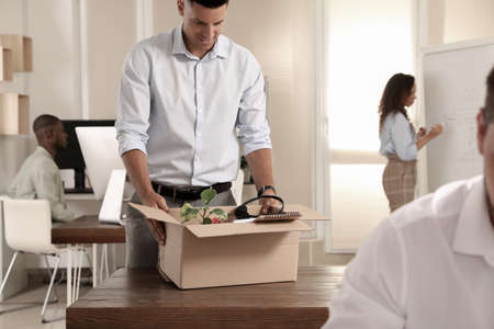 New coworker unpacking box with personal items at workplace in officeの写真素材
