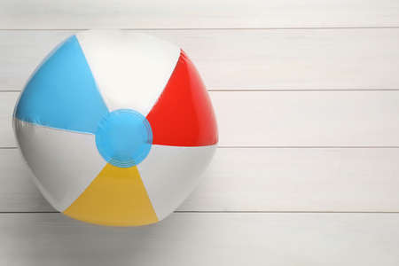 Colorful beach ball on white wooden background, top view. Space for text