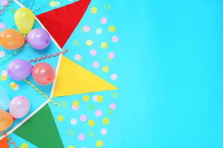 Bunting with colorful triangular flags, balloons, streamers and confetti on light blue background, flat lay. Space for textの写真素材